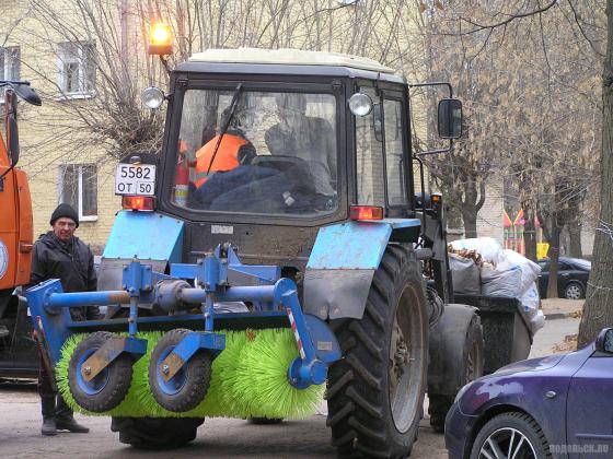 Трактор вывозит листву на помойку 