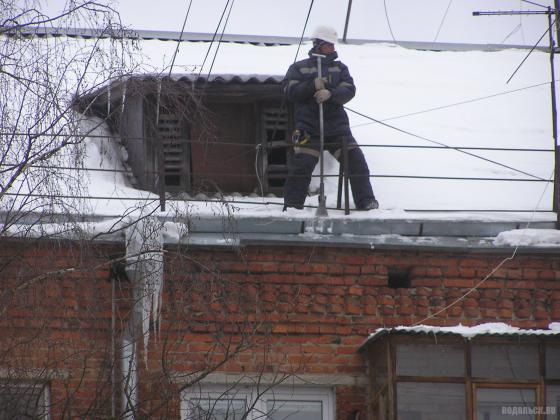 Альпинист скалывает лед на крыше 